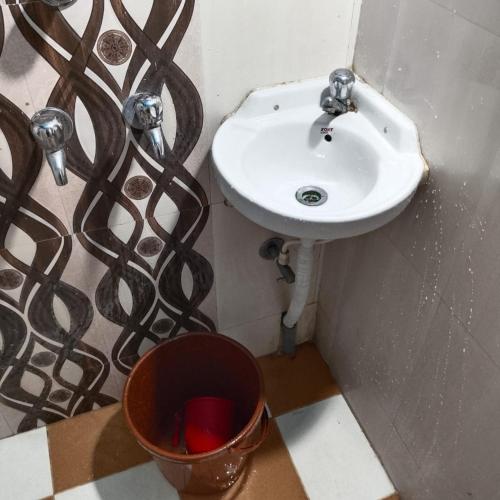 a bathroom with a sink and a bucket at Piyari Home stay 2 in Kolkata
