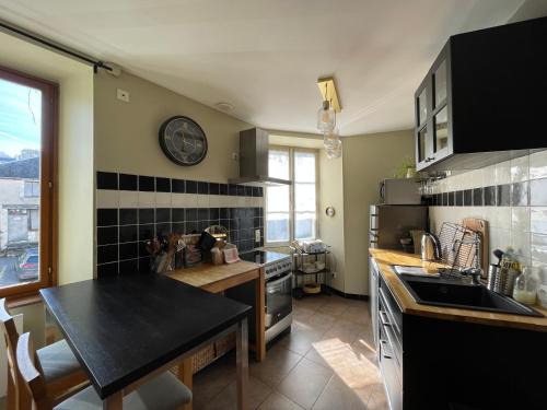 a kitchen with a table and a clock on the wall at Maison Les Fossiles in Sancerre