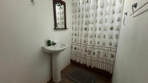 Baño blanco con lavabo y espejo en Ecoturístico La Tarde en Puerto Jiménez