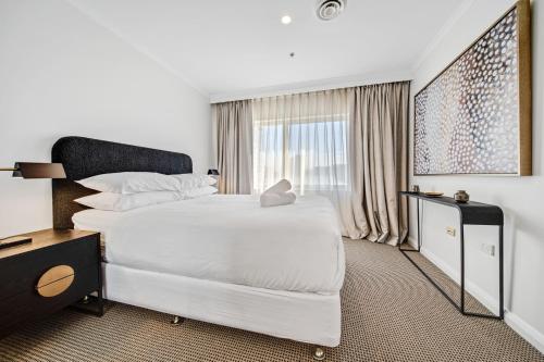 a white bedroom with a large bed and a window at Center 1-Bed with Sauna, Gym, BBQ & Parking in Canberra