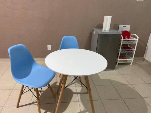 un tavolo bianco e due sedie blu in una stanza di Departamento completo cerca del Aeropuerto a Mérida