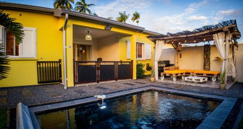 a yellow house with a swimming pool in front of it at Villa Osao Panahy in Le Patelin