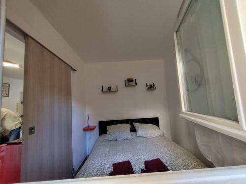 um pequeno quarto com uma cama e uma janela em Charmant T2 RD jardin grande terrasse coeur ville plage 2 m clim garage wifi em Sainte-Maxime