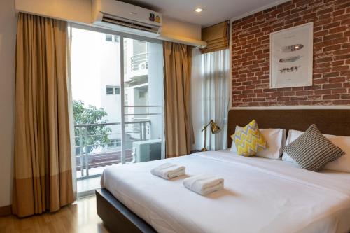 a bedroom with a large bed and a large window at GO INN Thonglor 23 โกอินน์ ทองหล่อ 23 in Khlong Toei