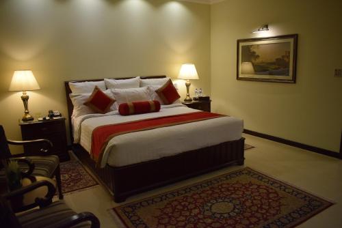 a bedroom with a bed with two lamps and a rug at Faletti's Hotel Lahore in Lahore
