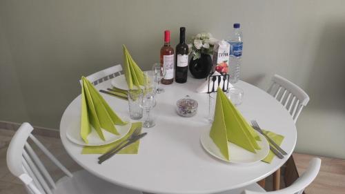 een witte tafel met groene servetten en wijnflessen bij Panorama Sea Esta 1 bedroom with sea view in Perea