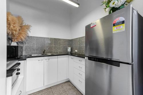 a kitchen with white cabinets and a stainless steel refrigerator at Private Windsor House Studios Apartment in Brisbane