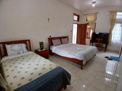 a bedroom with two beds and a cross on the wall at Hotel MBC Ruteng in Ruteng