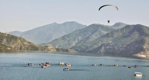a group of boats on a body of water with mountains at Hills Weather Homestay in Kanatal