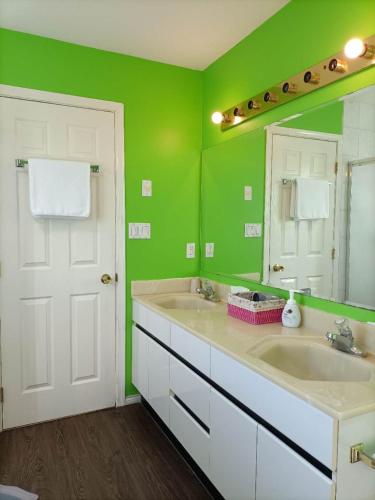 Baño verde con 2 lavabos y espejo en LLT HomeAway, en Vancouver