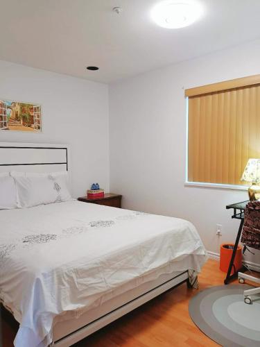 um quarto com uma cama branca e uma janela em LLT HomeAway em Vancouver