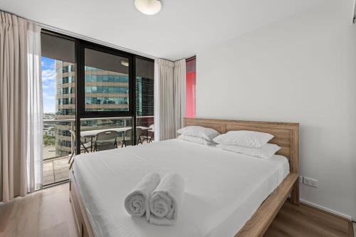 um quarto com uma cama branca e toalhas em Brisbane on Felix Luxury Suites em Brisbane