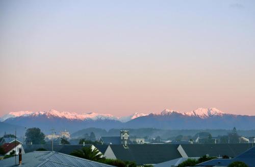 a view of snow capped mountains from a city at Revell St Beach Bungalow in Hokitika