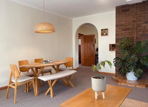 a dining room with a table and chairs and a plant at Revell St Beach Bungalow in Hokitika