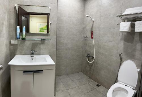 y baño con aseo, lavabo y ducha. en Forgather B&B, en San-min