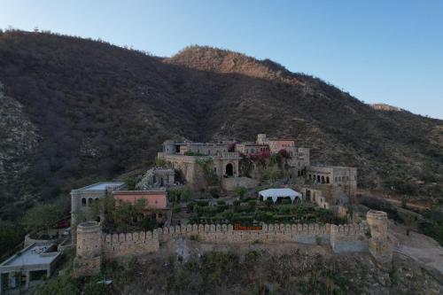 a building on top of a hill with a mountain at Fort Dadhikar, Alwar in Alwar
