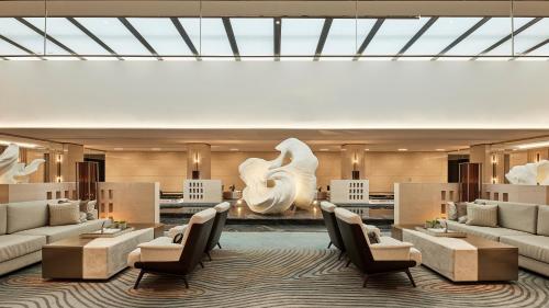 a hotel lobby with couches and tables and a sculpture at Four Points by Sheraton Xi’an High-Tech Zone in Xi'an
