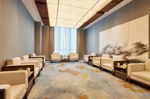 a waiting room with white chairs and a painting on the wall at Four Points by Sheraton Xi’an High-Tech Zone in Xi'an