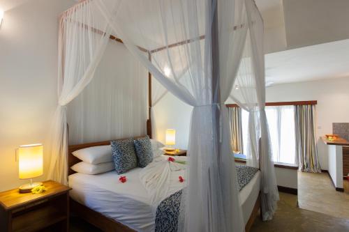 a bedroom with a canopy bed with white curtains at L'Hirondelle Self Catering Guest House in Praslin