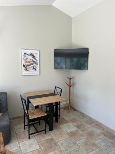 a dining room with a table and chairs and a tv at Gîte La maison dans l'Olivette in Oraison