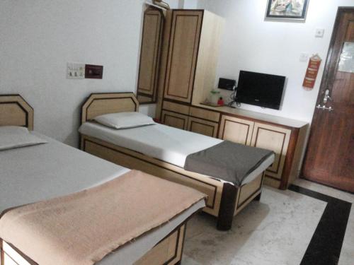 a room with two beds and a flat screen tv at Kuber's Residency in Mahad