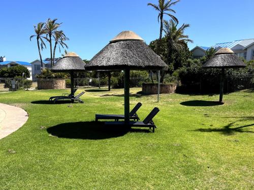 two chairs and umbrellas on a lawn with palm trees at Pinnacle Lodge 1089 in Dana Bay