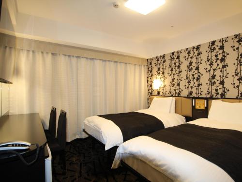 富山市にあるアパホテル 富山駅前のベッド2台とデスクが備わるホテルルームです。