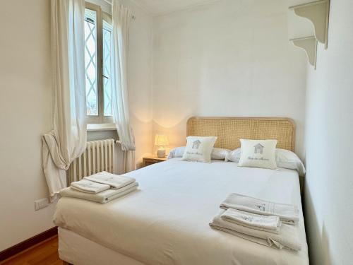 Un dormitorio con una cama blanca con toallas. en Maison Cirì, en Forte dei Marmi