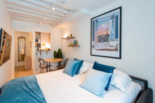 - une chambre avec un lit doté d'oreillers bleus et d'une table dans l'établissement Amazing studio on the most prestigious street, à Paris