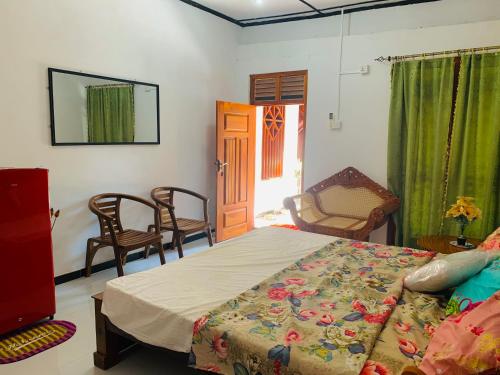 a bedroom with a bed and chairs and a door at Shehan Villa in Beruwala