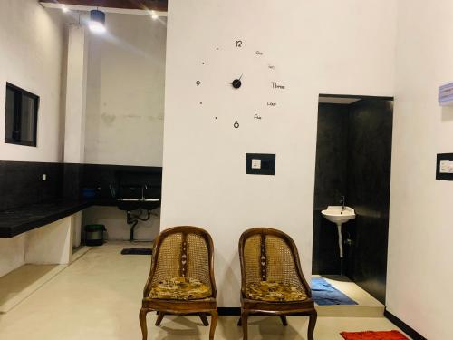 2 chaises dans une pièce avec une horloge sur le mur dans l'établissement Shehan Villa, à Beruwala