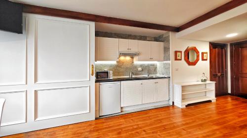 a kitchen with white cabinets and a wooden floor at Desconectaengalicia Estudio Puerta del Sol in Vigo