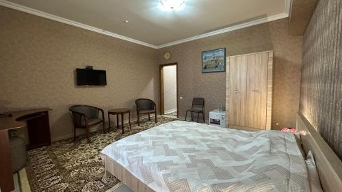a bedroom with a bed and a table and chairs at Cannes Hotel in Shymkent