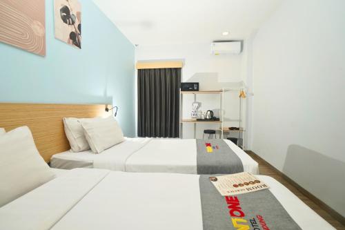 a hotel room with two beds and a desk at Front One Hotel Pasir Koja Bandung in Bandung