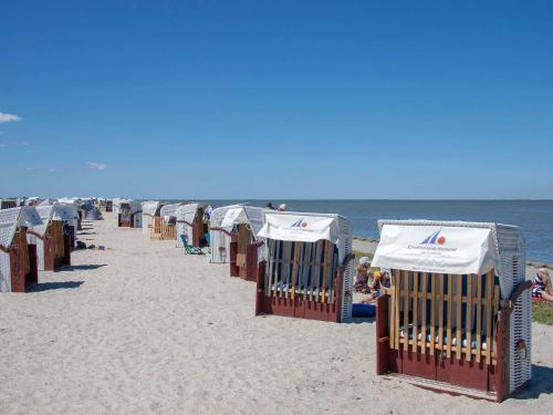 a row of beach chairs and umbrellas on the beach at Ferienhaus Harlesiel in Harlesiel