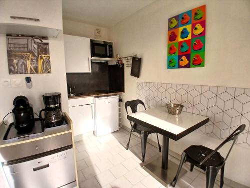 une petite cuisine avec une table et des chaises. dans l'établissement le dhuoda climatisé, à Nîmes