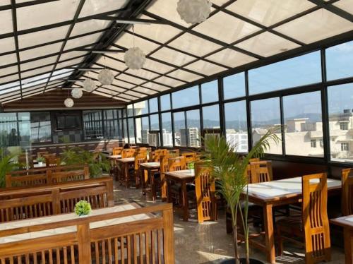 a restaurant with wooden tables and chairs and windows at Hotel Royal Stay , Katra in Katra