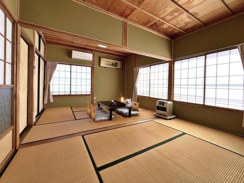 Großes Zimmer mit Fenstern und einem Tisch. in der Unterkunft Guest House Korasshai Nakajo in Tōkamachi