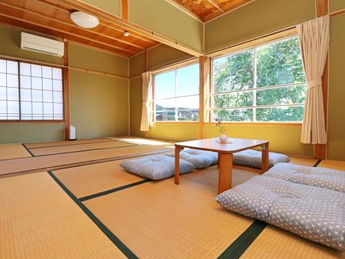 um quarto com uma mesa e algumas janelas em Guest House Korasshai Nakajo em Tokamachi