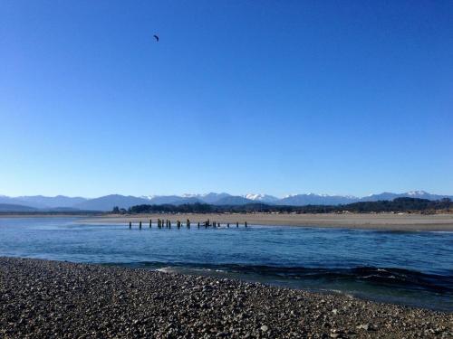 a group of people standing on a beach near the water at Hokitika Beach Break in Hokitika