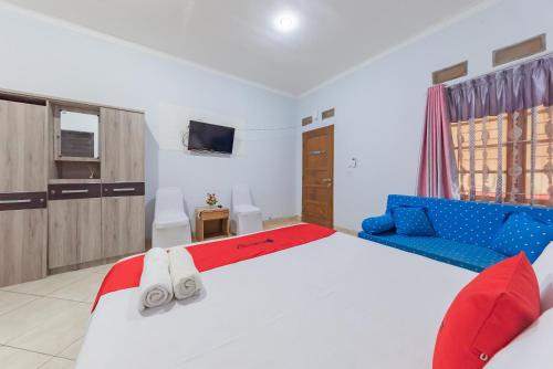 1 dormitorio con 1 cama blanca grande y 1 sofá azul en RedDoorz Syariah near Alun Alun Sumedang en Sumedang