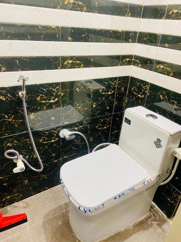 a toilet in a bathroom with a black tiled wall at Nirupam Sadan HomeStay in Vrindāvan