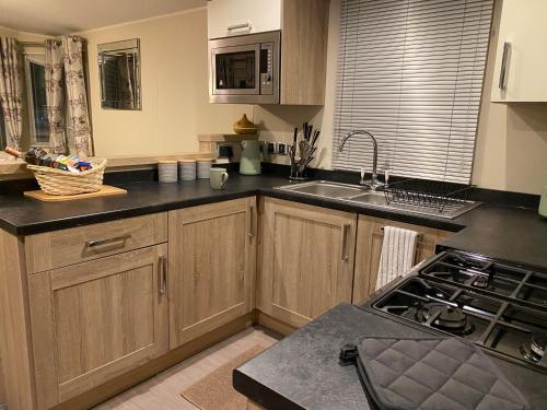 a kitchen with wooden cabinets and a sink and a stove at No. 40 Golf View in Jedburgh
