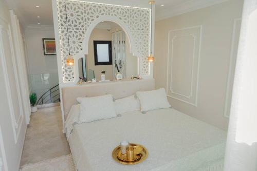 a white bedroom with a bed and a mirror at Maison SOUAD in Mahdia
