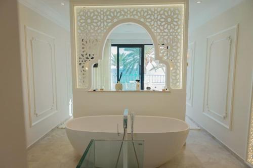 ein weißes Bad mit einer Badewanne und einem Spiegel in der Unterkunft Maison SOUAD in Mahdia