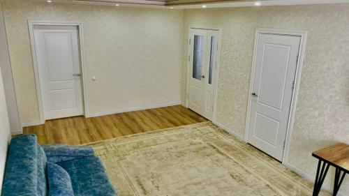 a living room with a blue couch and two doors at Guest house Roza in Kazarman