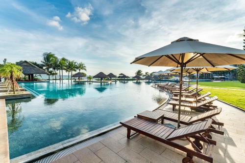 einen Pool mit Stühlen und einem Sonnenschirm in der Unterkunft Vietsovpetro Ho Tram Beach Resort & Spa in Hồ Tràm