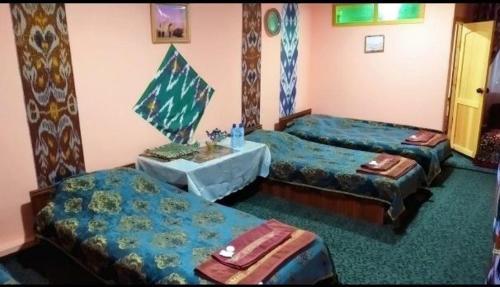 a room with three beds and a table in it at Fayz Hotel in Bukhara