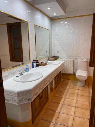 ein Badezimmer mit zwei Waschbecken, einem WC und einem Spiegel in der Unterkunft Villa privada piscina-tenis in Villarrobledo