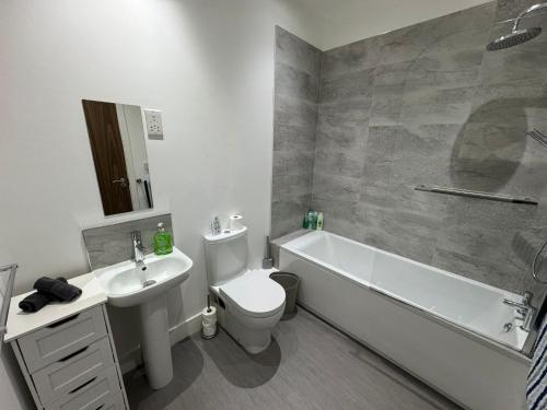 a bathroom with a sink and a toilet and a bath tub at Harbourside Apartment - 1 Bed Apartment in Whitehaven